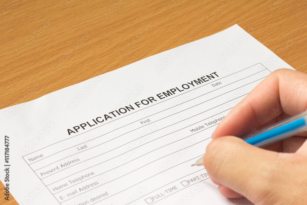Filling for application for employment form on wooden table Filling for application for employment form on wooden table