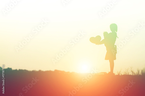 a silhouette of a happy young girl child in hands give heart th