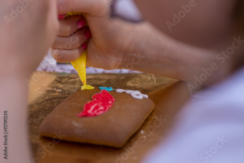 child draws on gingerbread with glaze