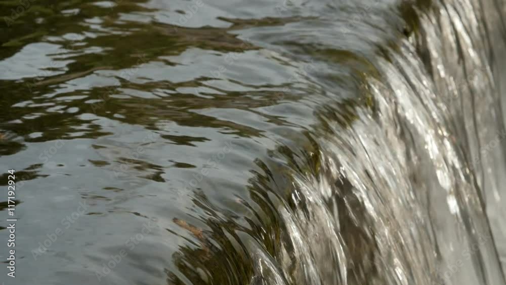 Peaceful flowing water in the river close-up. A small waterfall. Falling water lather. Peaceful flowing water in the river close-up. A small waterfall. Falling water lather.