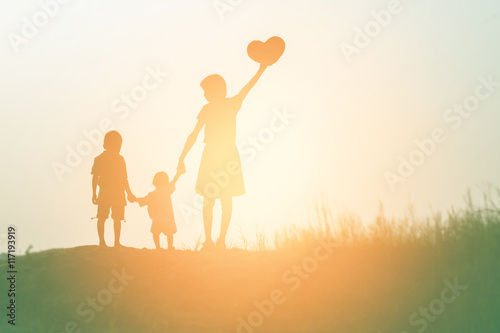 Mother encouraged her son outdoors at sunset, silhouette concept
