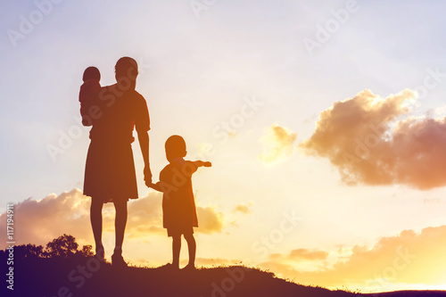 Mother encouraged her son outdoors at sunset, silhouette concept