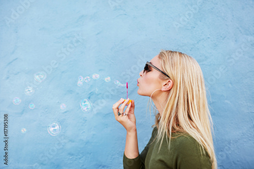 Billede på lærred Young beautiful woman blowing soap bubbles