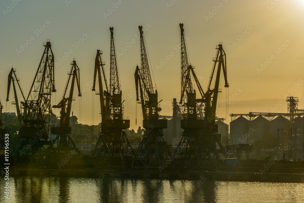 Obraz premium Port cranes against the evening sky in yellow tones on sunset