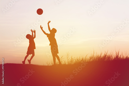 children playing ball on meadow, sunset, summertime