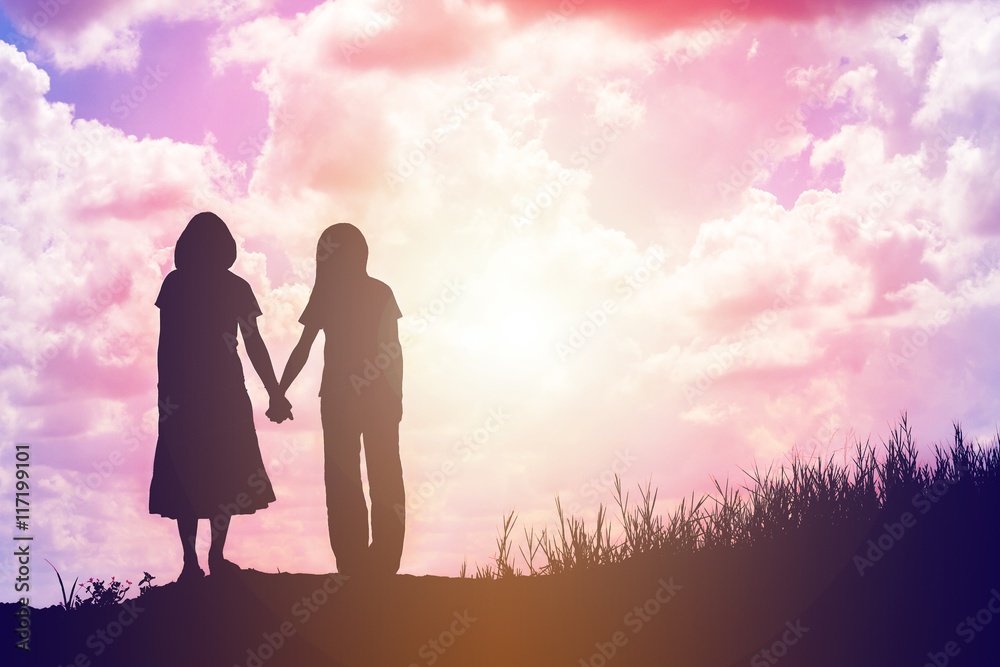 silhouette of two girls facing each other hold hands together