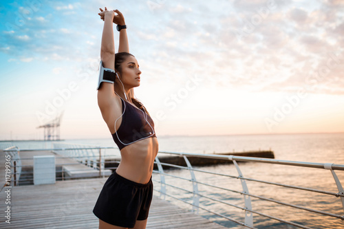 Fototapeta Naklejka Na Ścianę i Meble -  Young beautiful sportive girl training at sunrise over seaside.