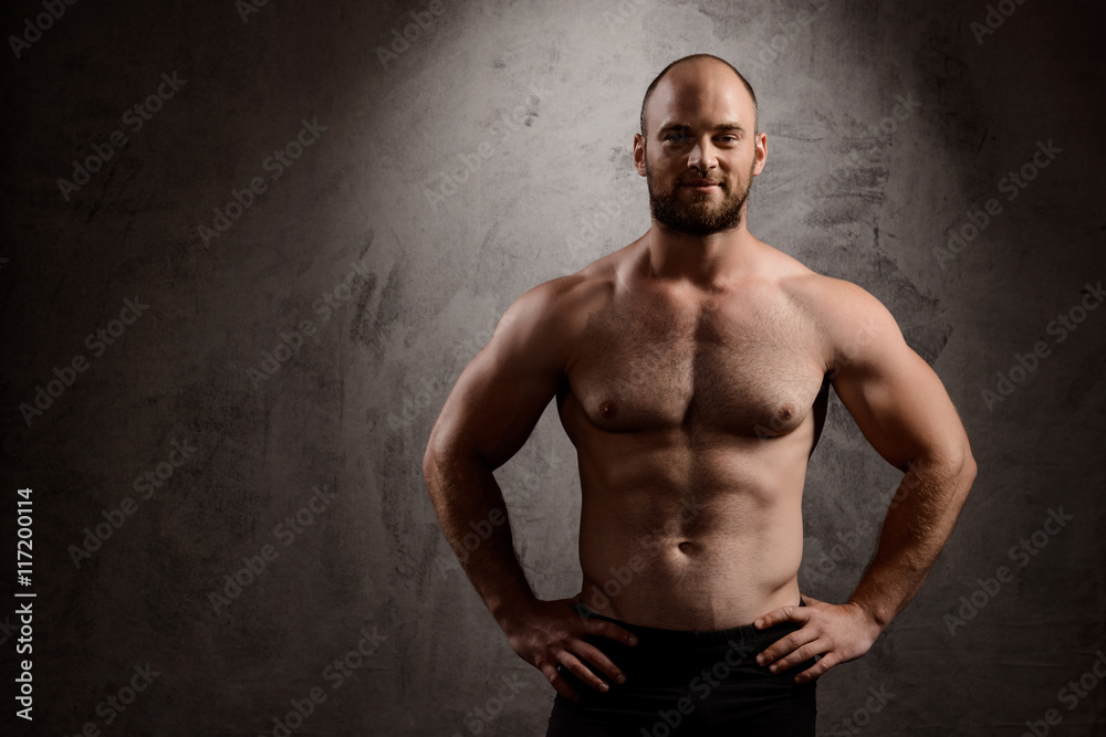 Portrait of young powerful sportsman over dark background.