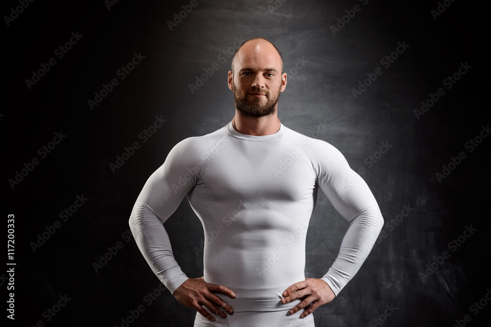 Young powerful sportsman in white clothing over black background. Young powerful sportsman in white clothing over black background.