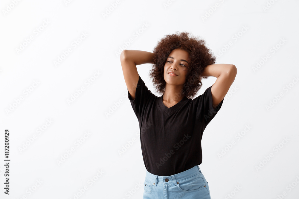 African girl smiling with hands behind head over light background. African girl smiling with hands behind head over light background.