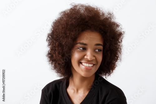 Beautiful african girl smiling over light background.