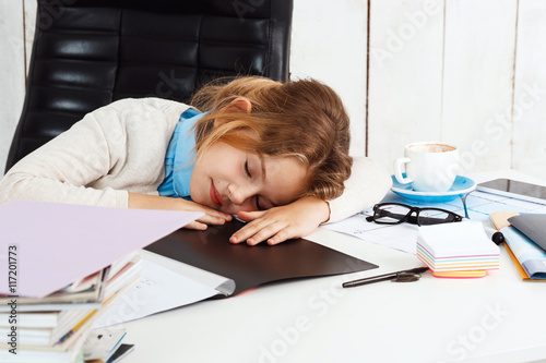 Young beautiful girl sleeping at working place in office.