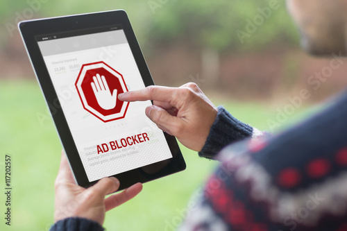 Young man using his tablet with ad blocker on the screen
