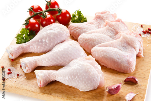Raw chicken wings and drumsticks on cutting board on white background 