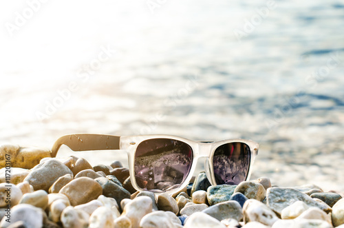 Black mirrored sunglasses on a stones. Shadow from glasses. Sunlight. Summer concept.