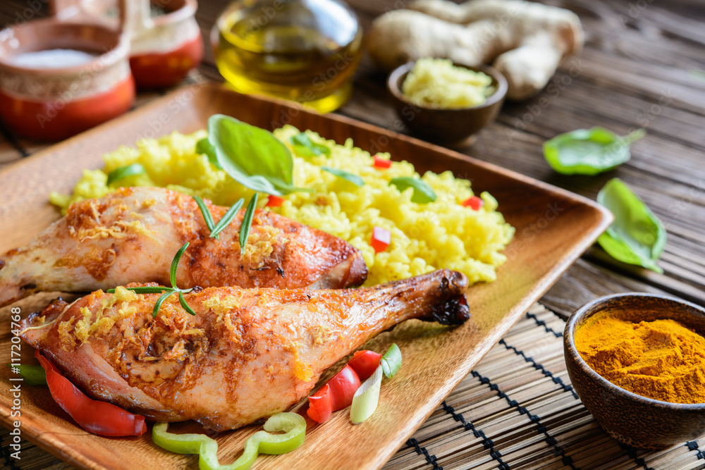 Baked chicken thighs with honey, grated ginger and rice with turmeric on a wooden background Baked chicken thighs with honey, grated ginger and rice with turmeric on a wooden background