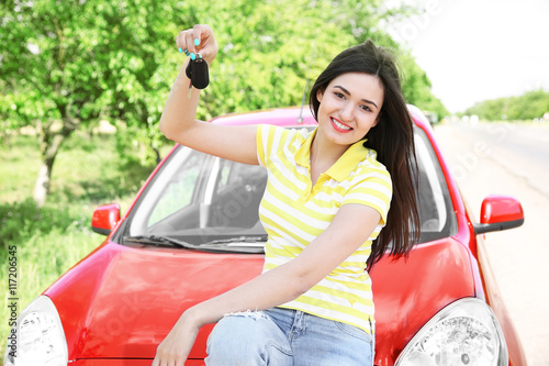 Woman holding key on red car