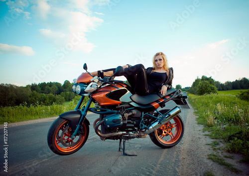 beautiful girl with red a motorcycle in the sun