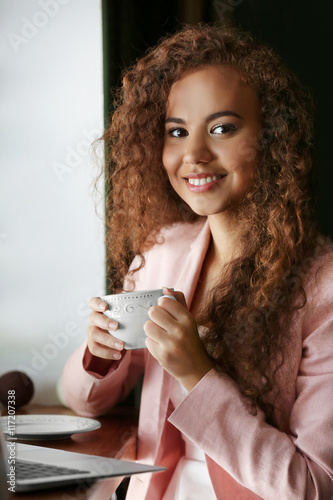 African American woman with a cup of coffee in cafe