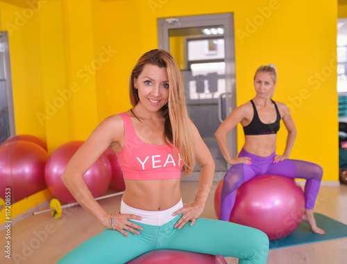 fitness, sport, training and lifestyle concept - happy women exercise on gymnastic balls in a gym