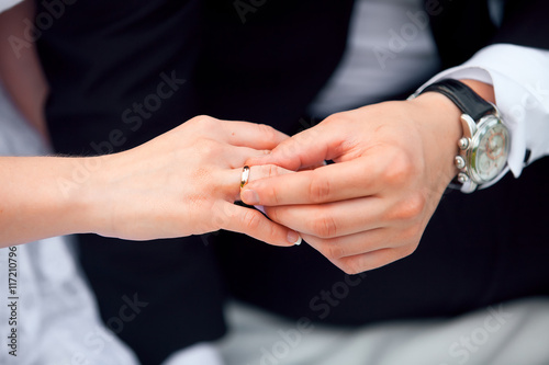 groom putting wedding ring on bride's finger