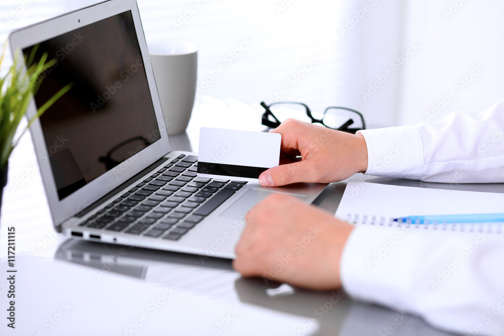 Close up of business woman hands using credit card and laptop computer Close up of business woman hands using credit card and laptop computer