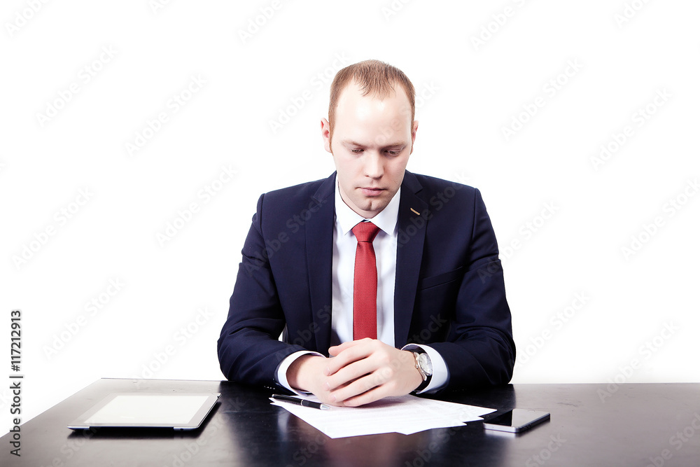 Finnish businessman in red tie at the table thought before signing the contract. Isolated on white background Finnish businessman in red tie at the table thought before signing the contract. Isolated on white background