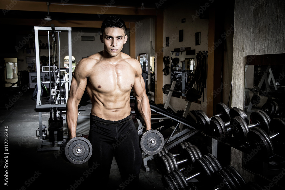 Young man exercising in dark and old gym Young man exercising in dark and old gym