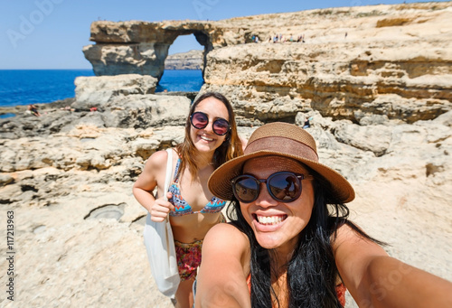 happy female friends taking selfie picture together on the rocky beach in Malta