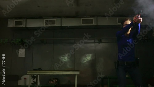 Beautiful young woman with the gun on an indoor shooting range. shoots a gun