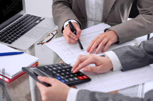 Two female accountants counting on calculator income for tax form completion hands closeup. Internal Revenue Service inspector checking financial document. Planning budget, audit concept