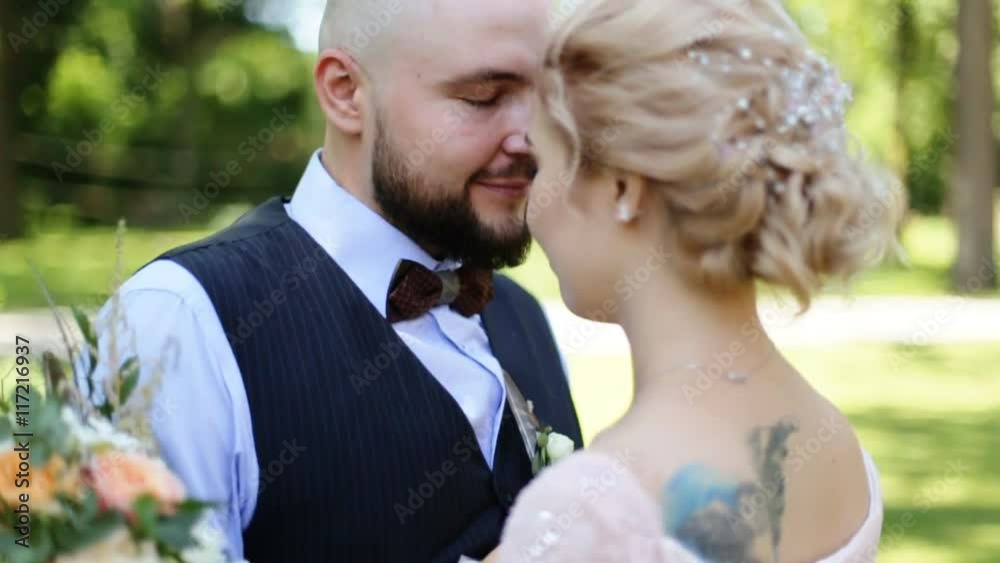 Beautiful bride and groom embracing and kissing on their wedding day outdoors Beautiful bride and groom embracing and kissing on their wedding day outdoors