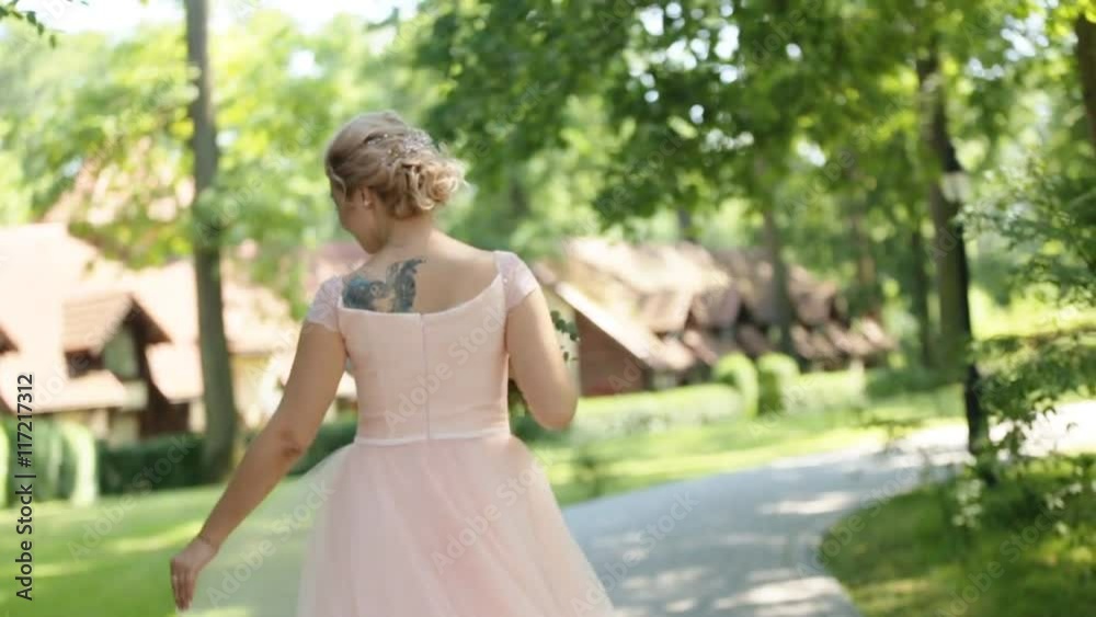 Close up of dreamy beautiful blonde bride with bouquet of roses dancing alone in the park and turning around Close up of dreamy beautiful blonde bride with bouquet of roses dancing alone in the park and turning around