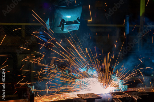 Welder is welding automotive part in factory
