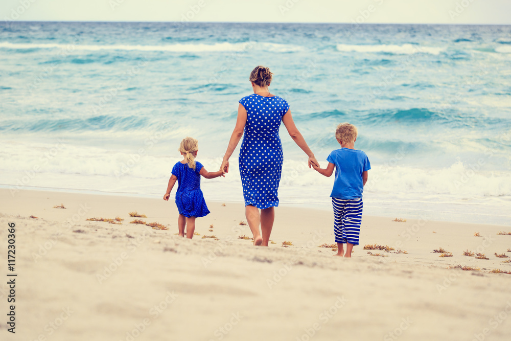 mother and two kids walking on the beach