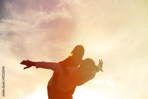 Father and little daughter silhouettes play at sunset