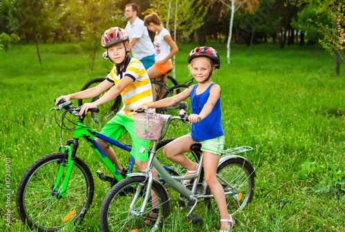 Family on bicycles on the grass field photo