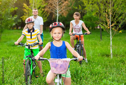 Family on bicycles on the grass field photo