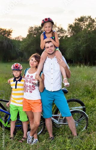 Family on bicycles on the grass field photo