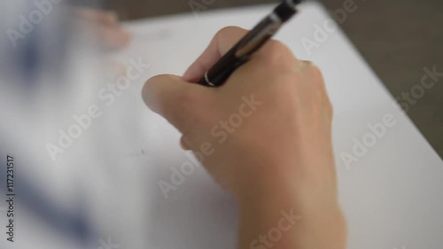 Closeup of woman's hand writing on paper with pen