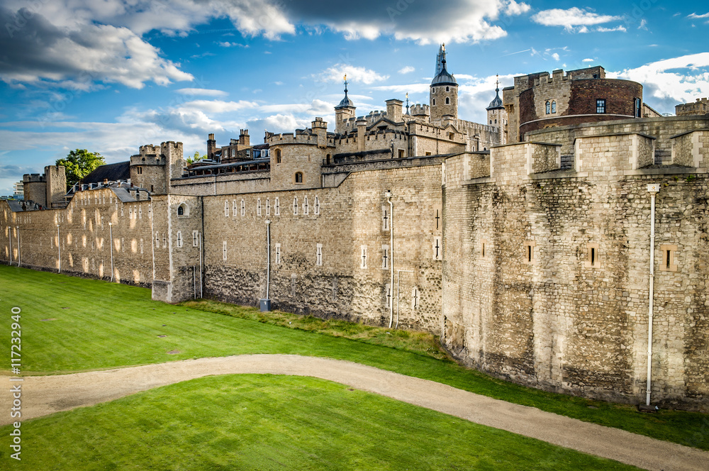 The wall of the Tower of London, and the green lawn outside of it on a summer sunny day. The historic castle is located on the north bank of the Thames and was built by William the Conqueror in 1078