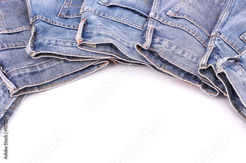 Stack of old blue jeans isolated on white