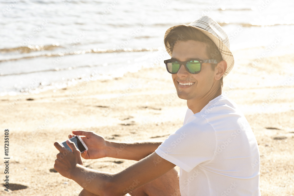 man on the beach smiling with mobile