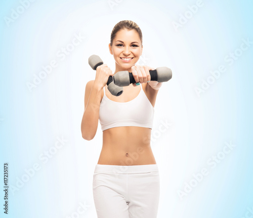 Young athletic woman training with dumbbells