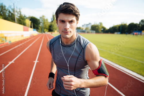 Close up portrait of a sports man running with earphones © Drobot Dean