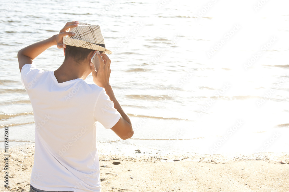 man calling by cell phone on the beach in summer