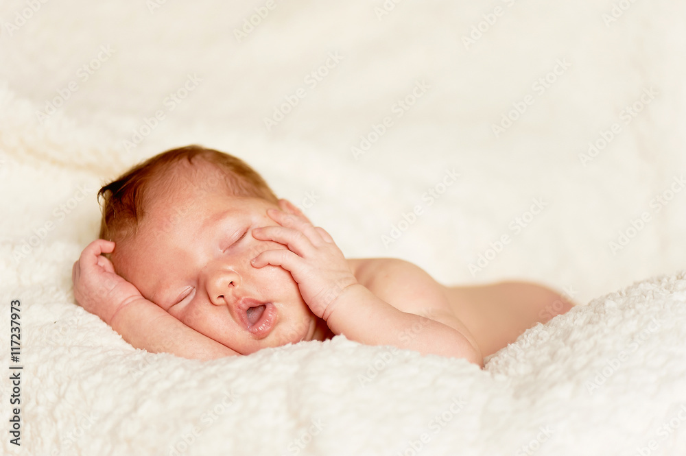 The baby, newly born, lies on the bright plaid and sleeping, handle the person