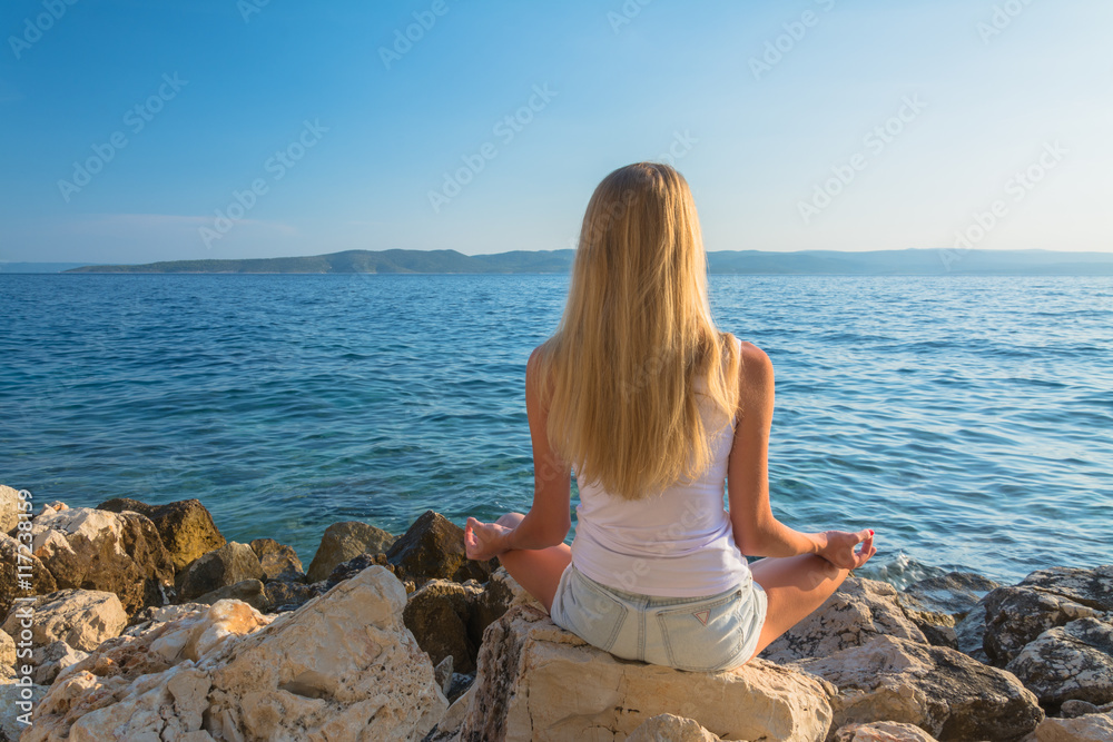 young beautiful woman meditation on beach in lotus position