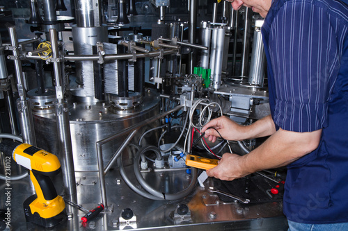 skilled worker while fixing a bottling plant during maintenance work