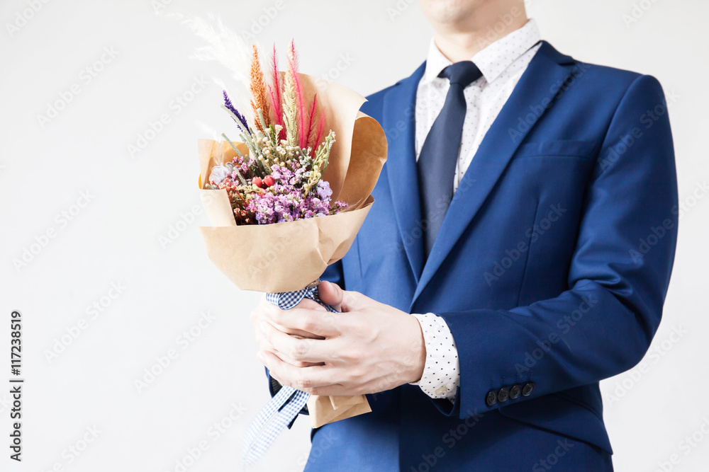 Young man in fashionable suit holding hipster hand-made bouquet